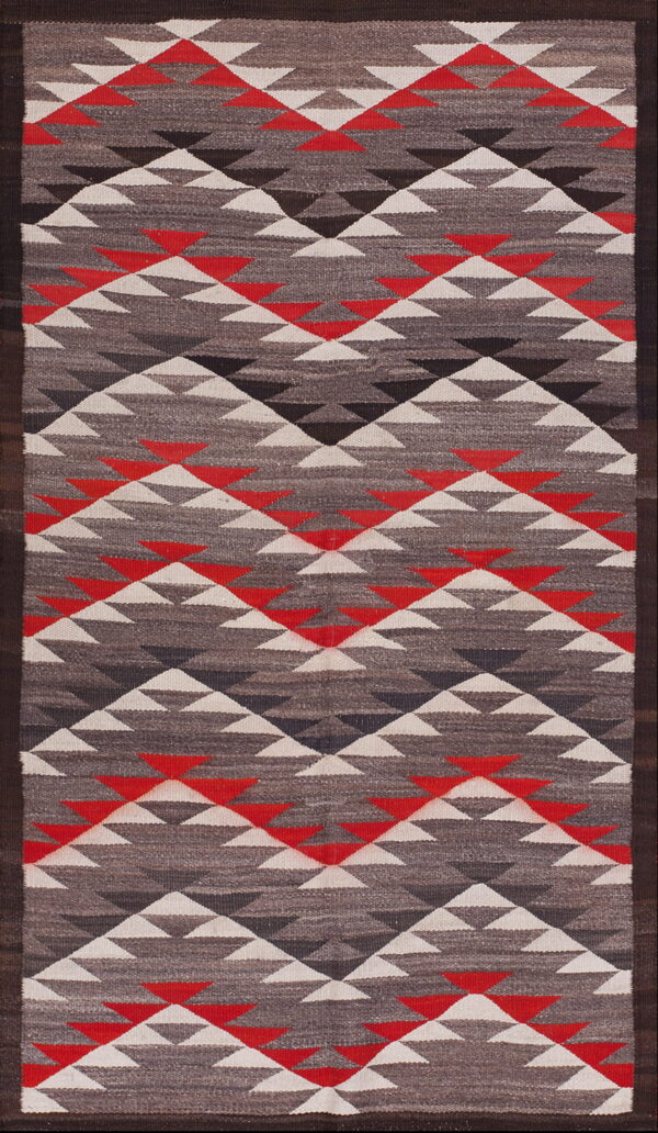 Flatweave rug with stacked triangles in red, white, and gray, framed by a dark brown border.