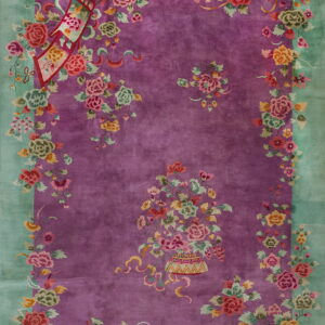 A plush magenta rug with a mint green border features a dense, colorful floral and ribbon pattern.