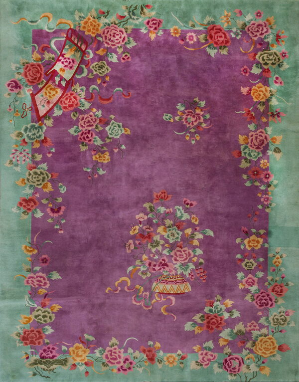 A plush magenta rug with a mint green border features a dense, colorful floral and ribbon pattern.