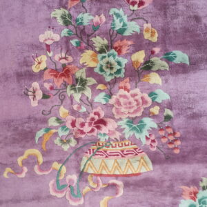 Plush purple rug featuring a large multicolored floral bouquet motif rising from a patterned vase.