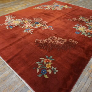 Rust-colored rug with scattered multicolor floral designs sits on aged, gray wooden floorboards.