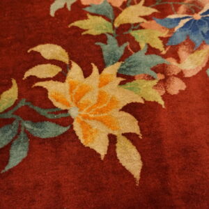 Burgundy high-pile rug detail with large floral pattern in yellow, blue, teal, green, and pink.