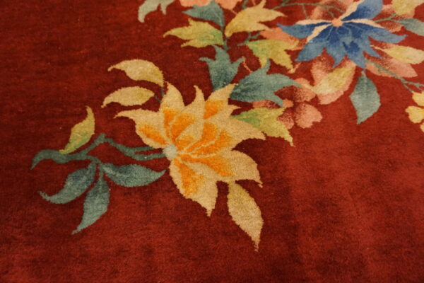 Burgundy high-pile rug detail with large floral pattern in yellow, blue, teal, green, and pink.