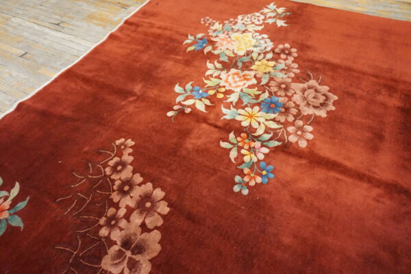 Rust rug with plush pile and colorful floral patterns rests on distressed light wood floors.