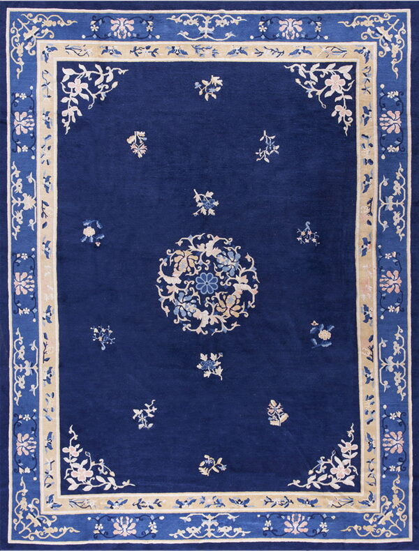 Blue rug with ornate floral patterns, a central medallion, and wide light tan borders.