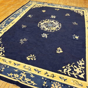 Deep blue rug featuring a cream central medallion and floral borders resting on wood flooring.