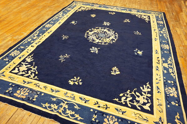 Deep blue rug featuring a cream central medallion and floral borders resting on wood flooring.