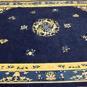 Navy blue rug features a central medallion and ornate gold floral borders on light wood flooring.