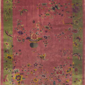 Pink field rug with an olive green border and intricate floral, butterfly, and hanging basket designs.