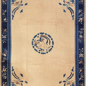 Beige rug featuring blue avian motifs and a wide navy border with a geometric key pattern.