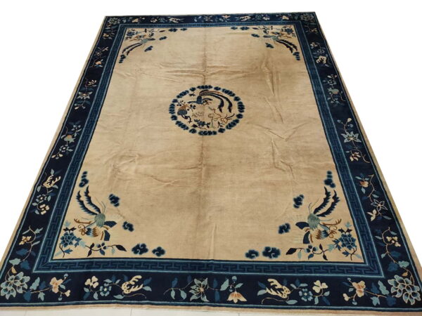 Beige field rug with dark blue borders featuring elaborate floral, vine, and bird motifs.