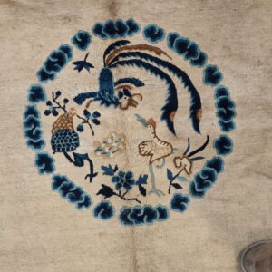 A light beige rug features a central blue and brown medallion depicting detailed birds and stylized floral motifs.