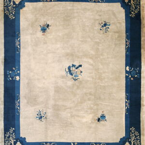 Light beige rug with a wide blue border featuring stylized pavilions, trees, and scattered floral motifs.