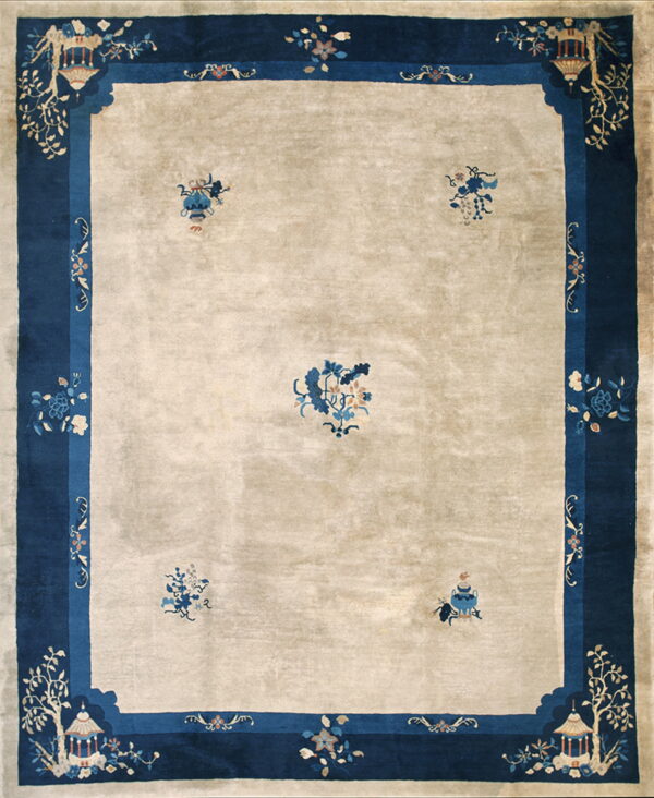 Light beige rug with a wide blue border featuring stylized pavilions, trees, and scattered floral motifs.