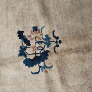 A soft, beige pile rug featuring a small botanical pattern in navy, teal, and muted coral.