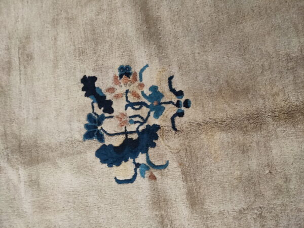 A soft, beige pile rug featuring a small botanical pattern in navy, teal, and muted coral.