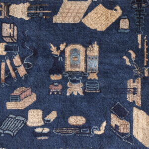 Close-up of a high-pile navy blue rug with stylized tan, beige, and blue abstract motifs.