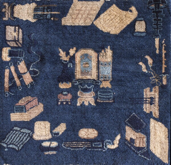 Close-up of a high-pile navy blue rug with stylized tan, beige, and blue abstract motifs.