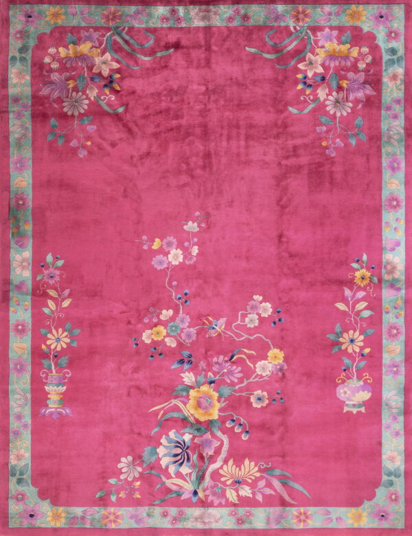 Deep pink rug with a velvety texture, featuring colorful floral sprays and a wide aqua-green scalloped border.