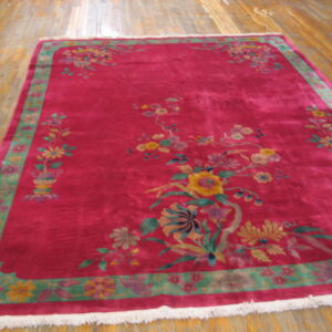 Fuchsia rug with colorful floral sprays and a wide sage green border on light plank wood floors.