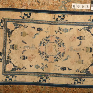Light beige rug with scattered blue, teal, and pink motifs, featuring a dark blue border on an orange patterned background.