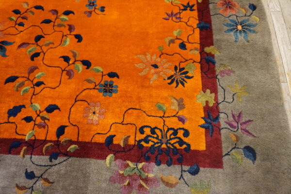 Detail view showing a vibrant orange field and taupe border accented with multicolored flowers and vines.
