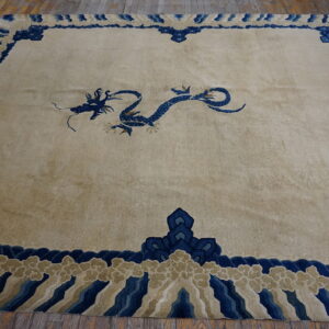 Beige rug with a central blue dragon motif and a decorative blue and tan border on wood planks.