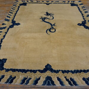Tan area rug with a dark blue stylized dragon and wave-like cloud border over plank flooring.