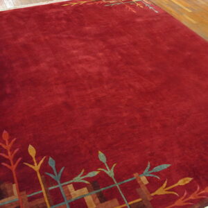 Burgundy cut pile rug featuring colorful botanical and geometric patterns at the top and bottom edges.