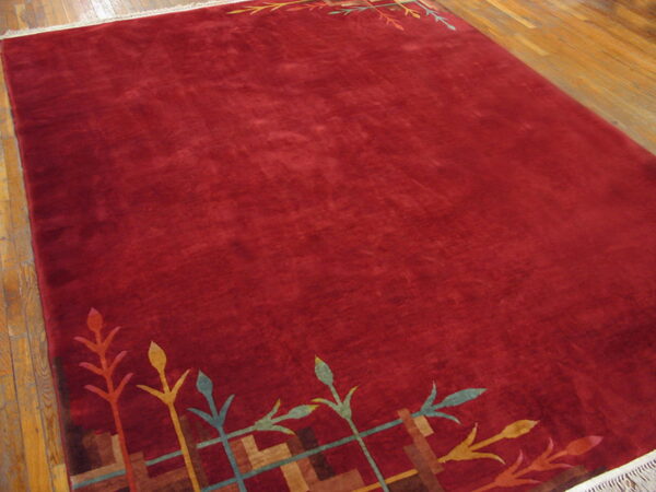 Burgundy cut pile rug featuring colorful botanical and geometric patterns at the top and bottom edges.