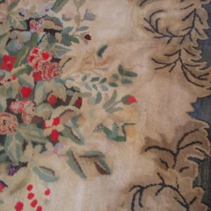 Close-up of a high-pile floral rug showing red, green, and beige colors next to dark wood flooring.