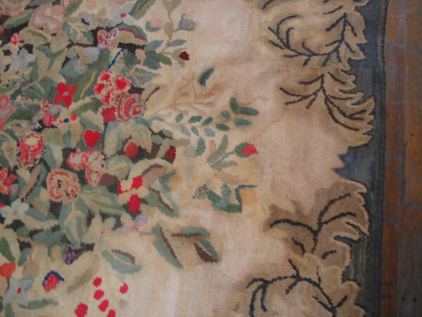 Close-up of a high-pile floral rug showing red, green, and beige colors next to dark wood flooring.