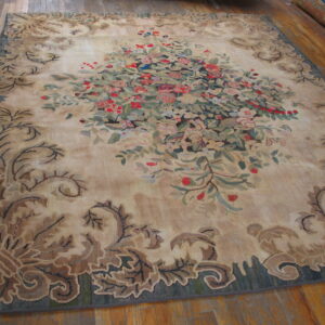 Beige rug featuring a vibrant floral center and a scrolling brown-and-green leaf border on wood flooring.