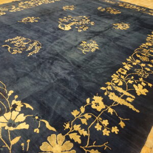 Navy blue rug featuring a vibrant gold floral border and scattered patterns on light wood flooring.