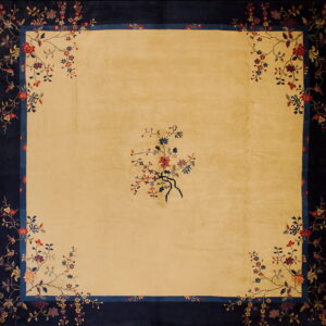 Gold square rug featuring a navy blue floral border and a sparse colorful botanical spray in the center.