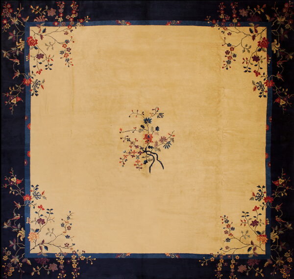 Gold square rug featuring a navy blue floral border and a sparse colorful botanical spray in the center.