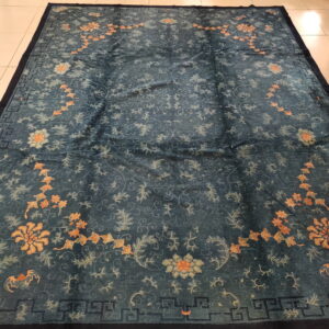 Deep teal rug with a sheen, featuring apricot floral patterns and a dark geometric border on light tile.