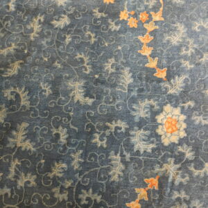 Blue high-density rug showing muted floral patterns, apricot accents, and a dark geometric border.