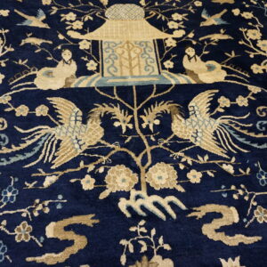 Navy blue rug with a dense pattern of tan birds, figures, flowers, and a central pavilion.