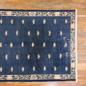 Dark blue rug with a geometric lattice field and light tan abstract symbols, bordered by beige scrollwork.