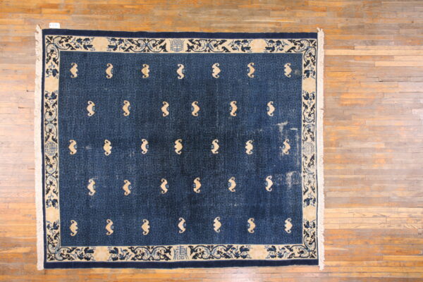Dark blue rug with a geometric lattice field and light tan abstract symbols, bordered by beige scrollwork.