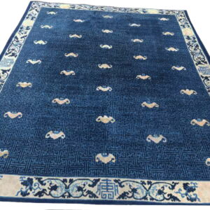 Blue rug with a subtle geometric grid field, scattered gold curved shapes, and an ornate cream border.
