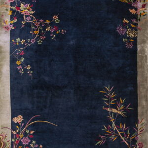 Plush dark blue rug bordered in muted gray, accented with multicolored flowers and branches.
