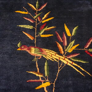 Dark blue pile rug featuring a decorative motif of a colorful bird perched on a leafy branch.