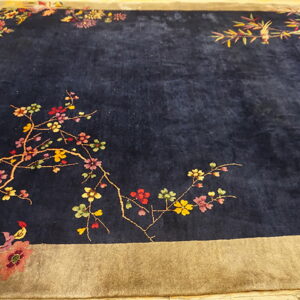 Dark blue high-pile rug featuring multicolored floral branches and a wide tan border.