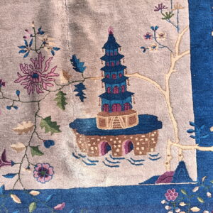 A close-up shows a blue and magenta pagoda design on a light tan rug field with a contrasting blue border.