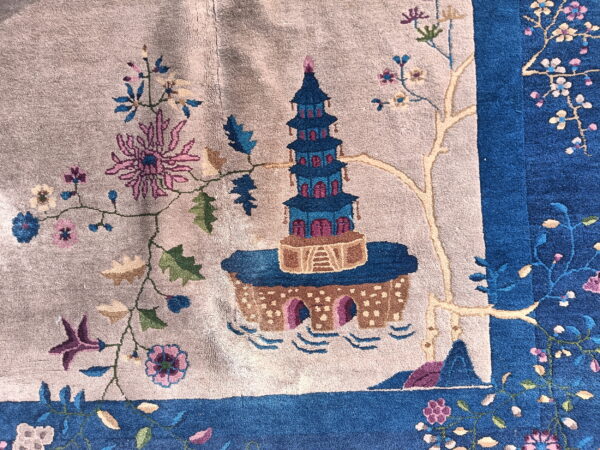 A close-up shows a blue and magenta pagoda design on a light tan rug field with a contrasting blue border.