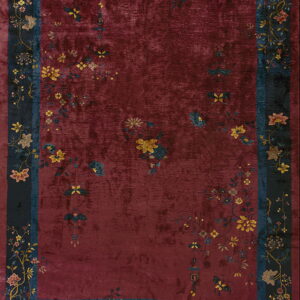 Low-pile, distressed burgundy rug featuring delicate yellow floral sprays and a wide dark navy pictorial border.