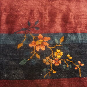 Plush burgundy and navy striped rug detail shows an orange and gold floral vine pattern.