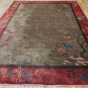 Large rug featuring a gray field with subtle motifs and a wide crimson border, resting on wood floorboards.
